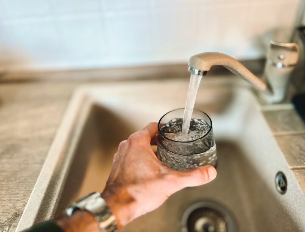 filling cup with water from the faucet to drink